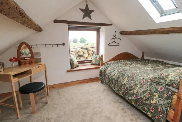 The Old Workshop mezzanine bedroom with exposed beams and countryside views