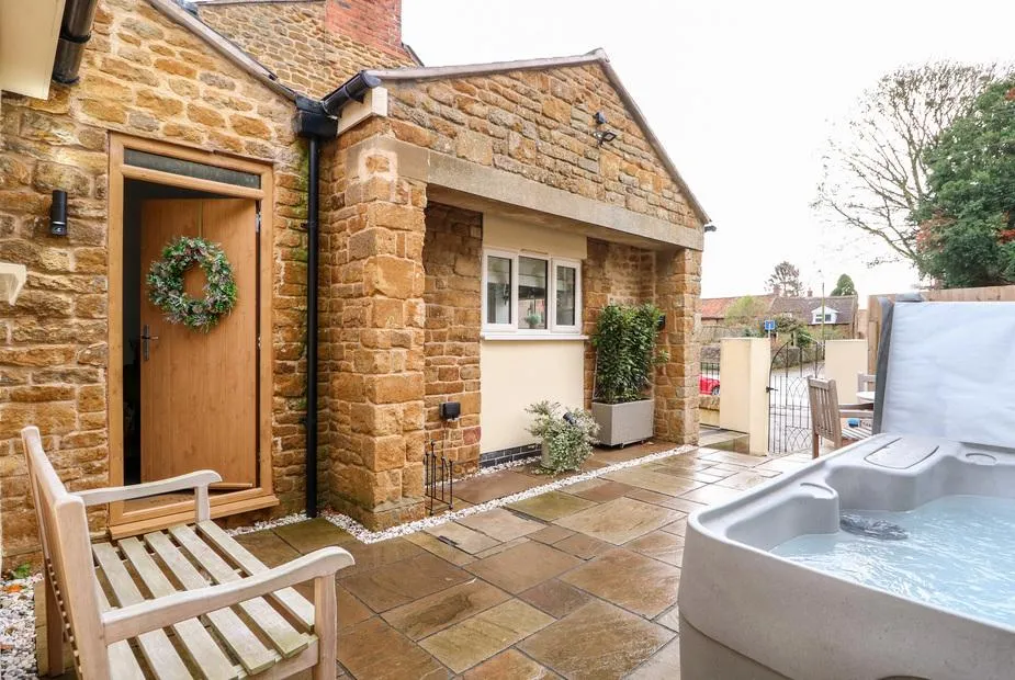 The Pinfold hot tub beside the honey-stone cottage frontage