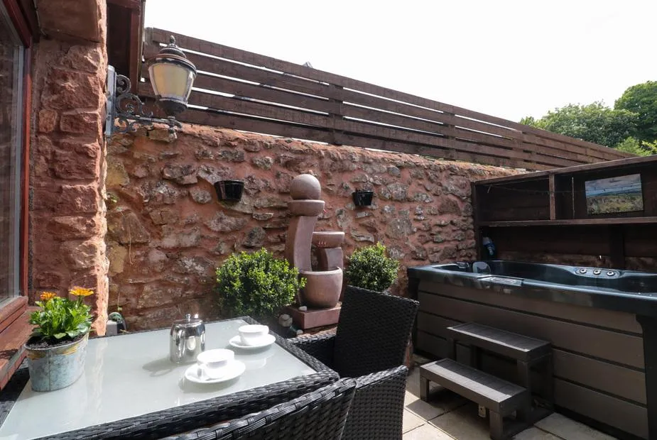 The Retreat courtyard hot tub with red sandstone wall and lanterns