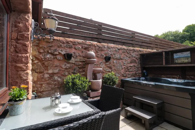 The Retreat courtyard hot tub with red sandstone wall and lanterns