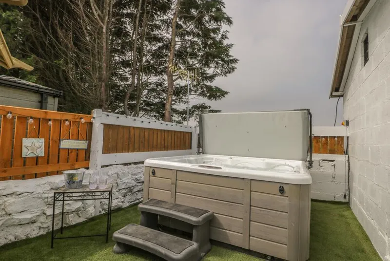 The Sequoia hot tub with steps and string lights in tree-lined garden