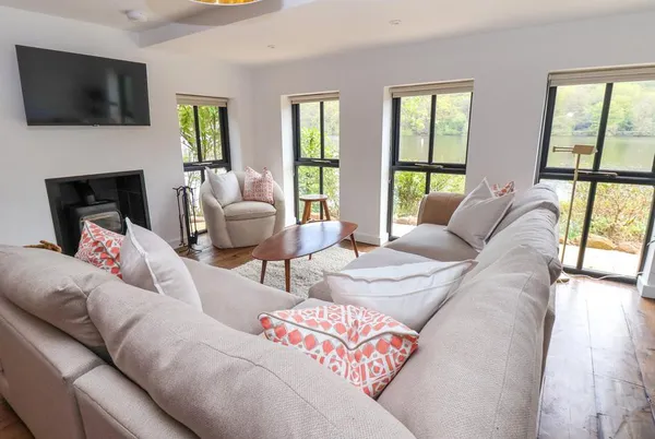 The Sheiling living room with wood burner and lake views through windows