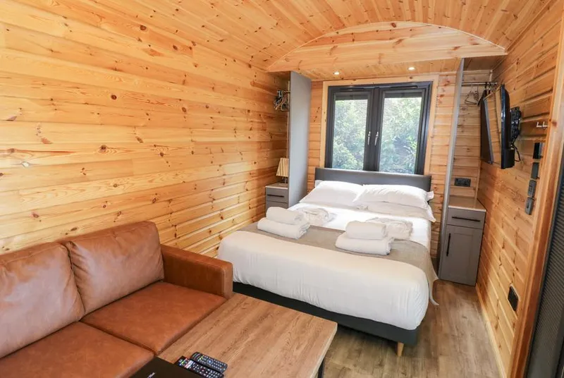 The Shepherds Hut at Bridge Lake Farm & Fishery wood-lined interior with bed and sofa