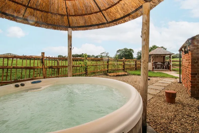 The Shooting Folly wood-fired hot tub under thatched canopy