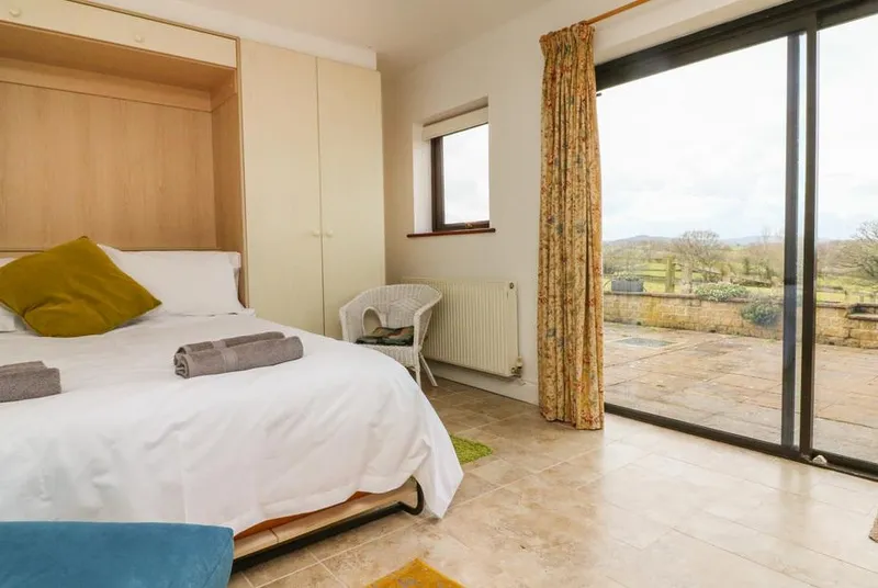 The Stables bedroom with sliding glass doors open to patio and countryside views