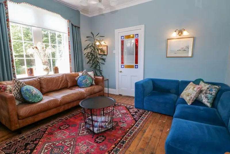 The Stone Masons House living room with leather sofas and stained glass