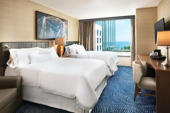 Two beds in a hotel room with a large window