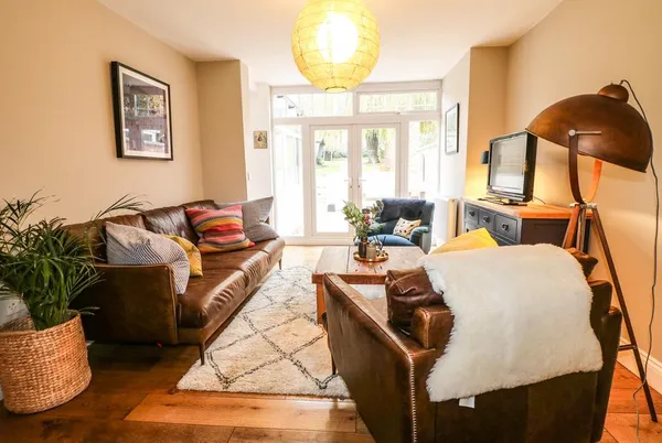 The Willows cosy lounge with leather sofa and garden doors
