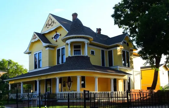 Yellow Victorian house with white trim and a wrap-around porch