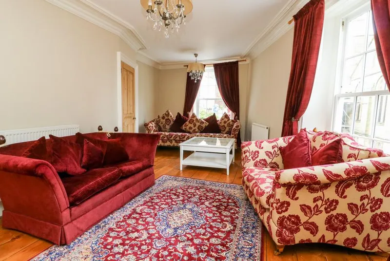Trillo House living room with red velvet sofas and chandelier