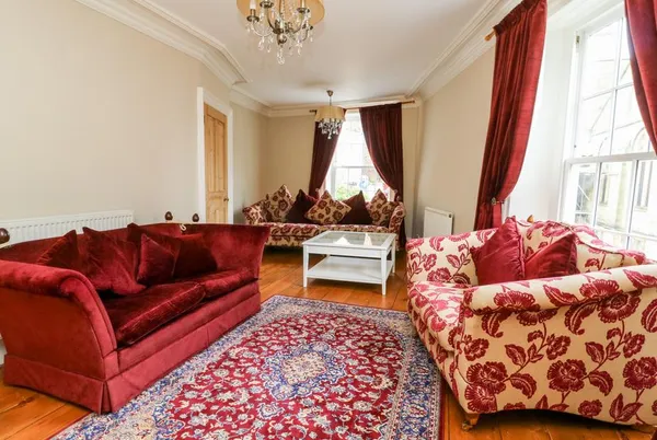 Trillo House living room with red velvet sofas and chandelier