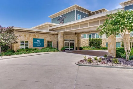 Stone and teal Homewood Suites entrance with a covered driveway