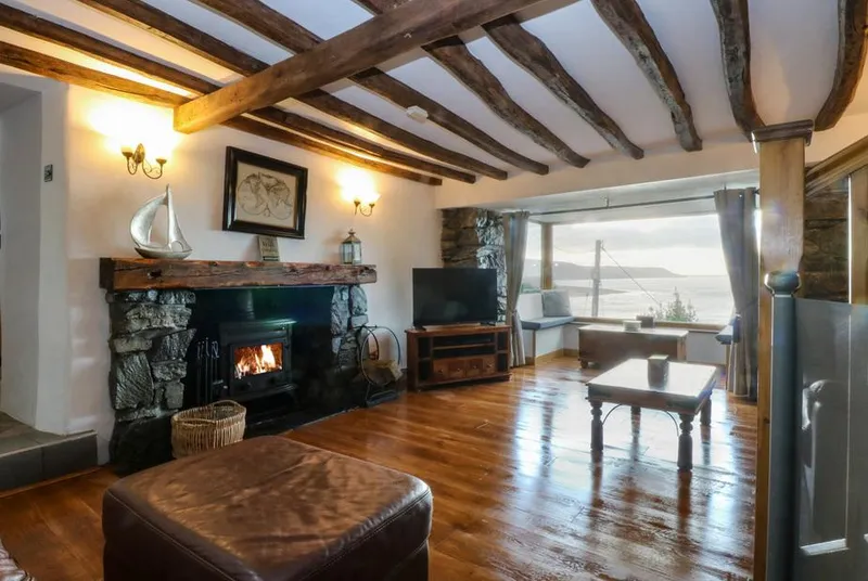 Ty'n-Y-Ffynnon Cottage lounge with wood burner and harbour glimpse