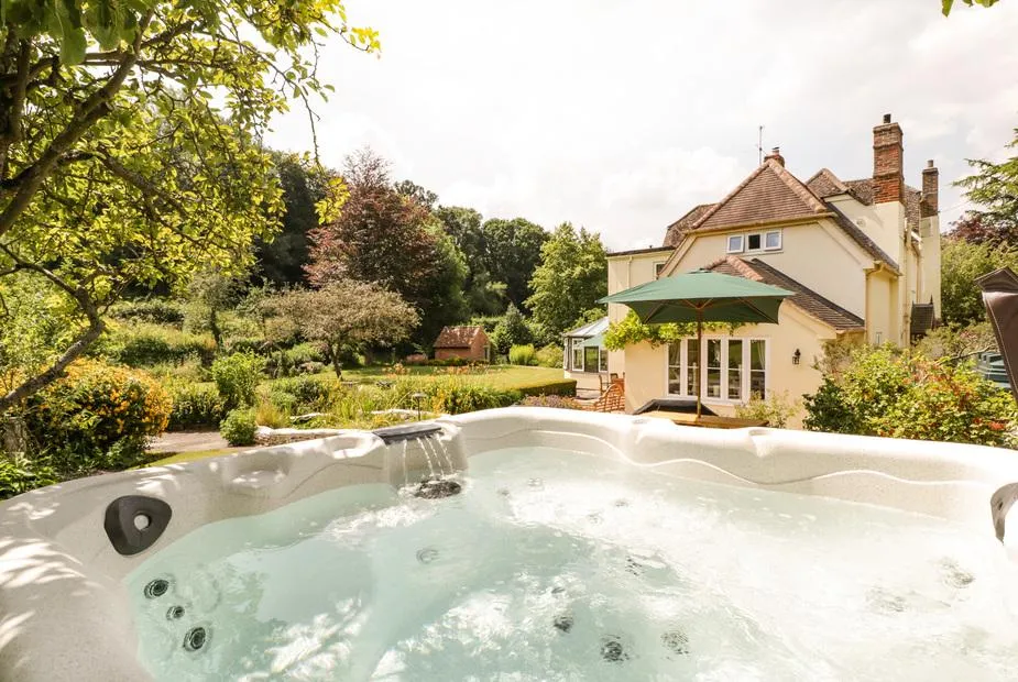 Valley House hot tub with jets running and house in sunny garden behind