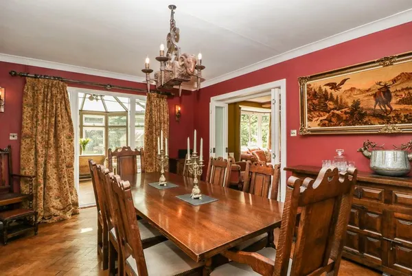 Valley House formal dining room with red walls, chandelier and 10-seater table