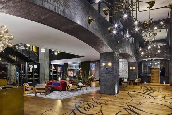 Lobby with dark brick arches and trumpet-horn chandeliers