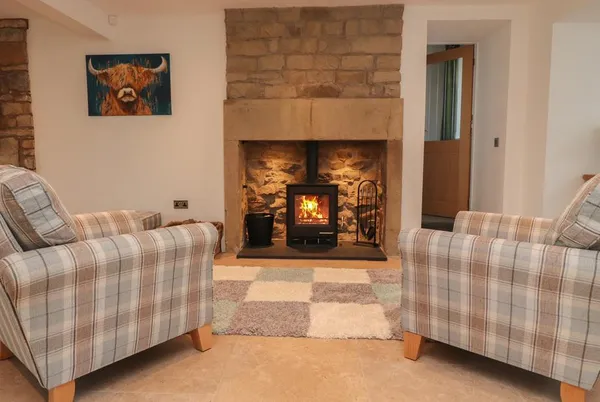 Vine Cottage lounge with stone fireplace and armchairs