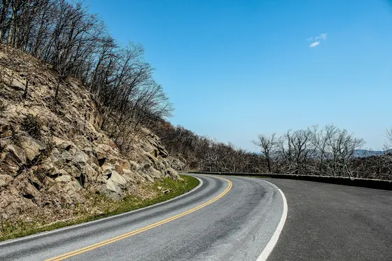 Skyline Drive curving around a rocky hillside under a blue sky