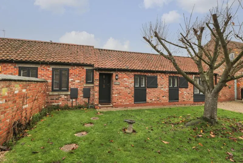 Well Cottage brick barn conversion with lawn and tree