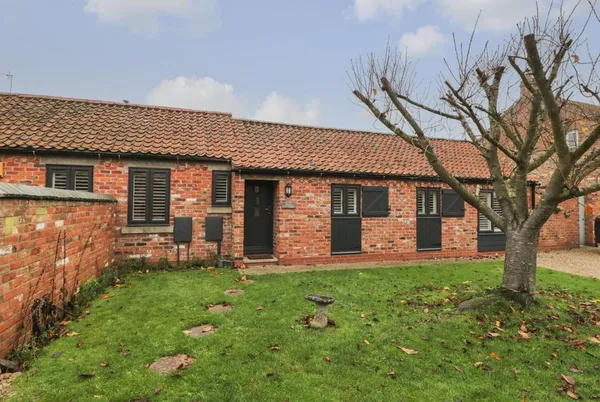 Well Cottage brick barn conversion with lawn and tree
