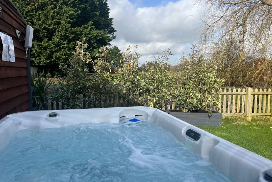Willow Pod bubbling hot tub surrounded by lush garden greenery