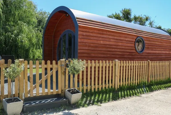 Willow Pod barrel-shaped exterior with porthole windows and olive trees