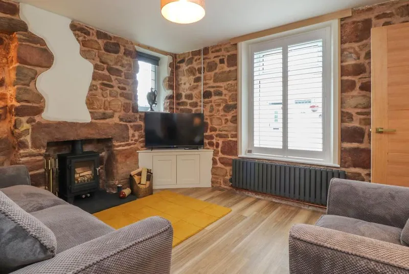 Woodman Cottage lounge with stone walls and a wood-burning stove