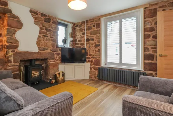 Woodman Cottage lounge with stone walls and a wood-burning stove