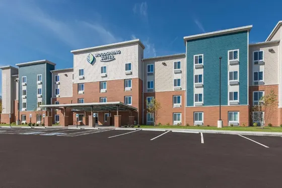 Four-story hotel with red brick, teal siding, and empty lot