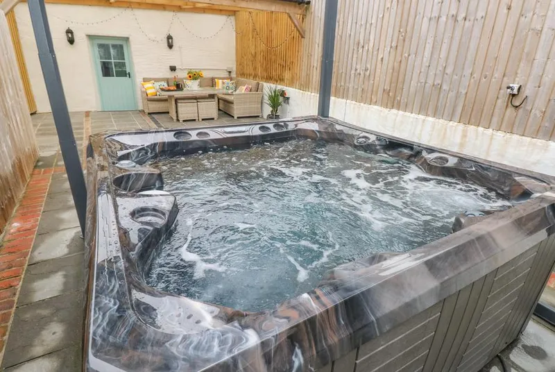 Y Beudy large hot tub under the Covana lid with outdoor seating beyond