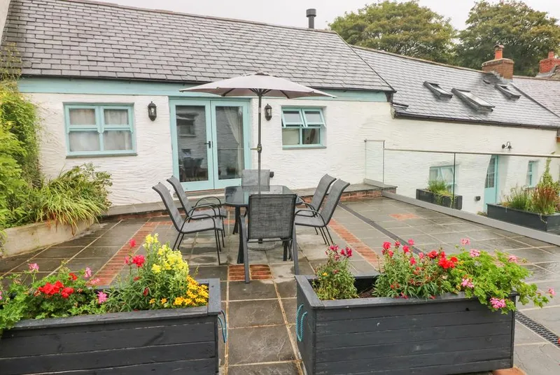 Y Beudy cottage exterior with flower planters and dining terrace
