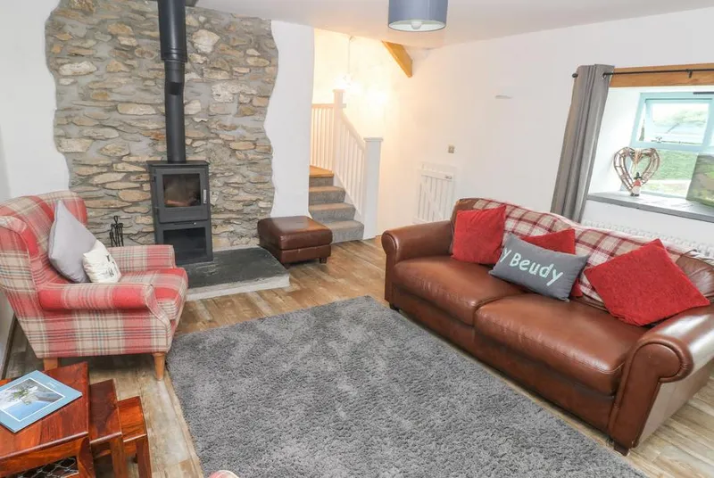 Y Beudy lounge with stone fireplace and leather sofa