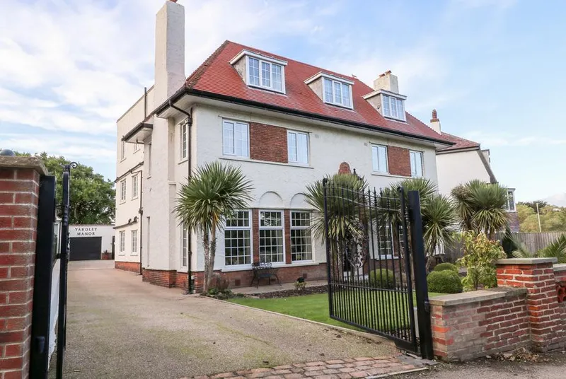 Yardley Manor white rendered facade with iron gates and palm trees
